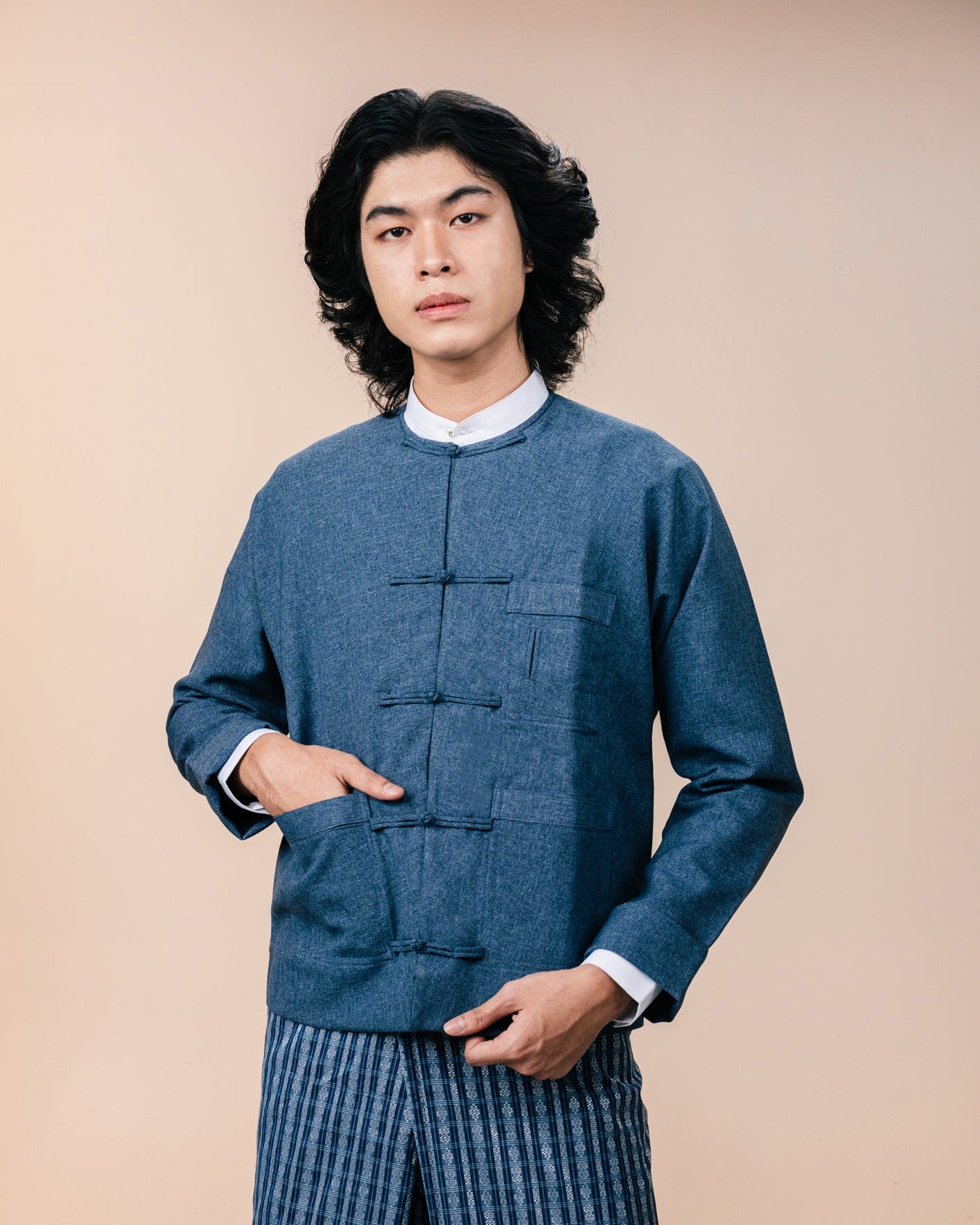 Person wearing a blue traditional outfit with a beige background